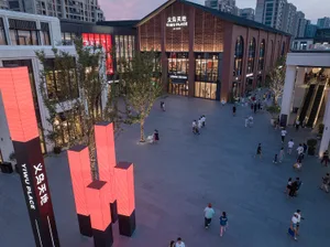 人們走在都市廣場中，周圍是混凝土與玻璃建築，並由LED燈光照亮。