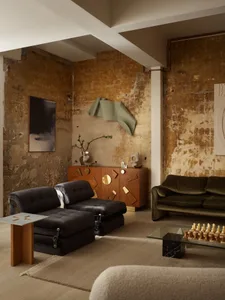 Industrial living room featuring metal and wood furniture and concrete walls.