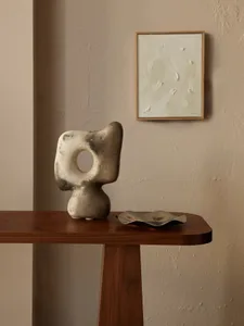 Modern decoration featuring a metal and ceramic object displayed on a wooden table.