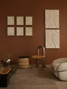 A modern living room with abstract art on the wall, featuring a glass coffee table, a beige upholstered chair, and various sc