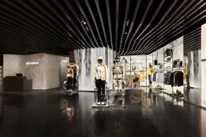 一間以混凝土材質打造的現代零售店，展示運動服飾與配件的人體模型。