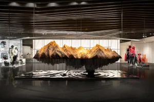 A modern storefront constructed from metal and glass, featuring a large model of mountains.