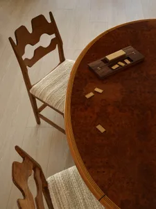 A close-up of a wooden dining table with two chairs next to it.