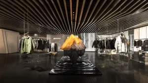 A modern retail store interior featuring metallic materials and a prominent volcano sculpture.
