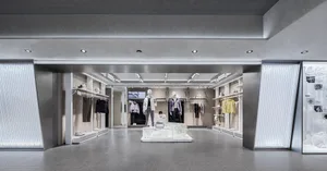 Modern retail store with concrete and metal interior, displaying clothing on mannequins.