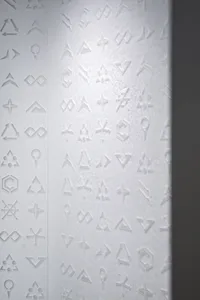Embossed symbols on a textured, white paper surface.
