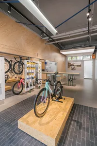 Modern interior of a bike shop featuring plywood, concrete, and steel elements.