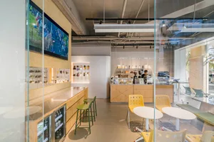 A modern coffee shop featuring wooden counters, glass display cases, and metal chairs.