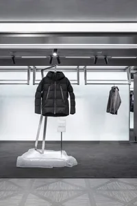 A black puffer jacket displayed in a modern retail fashion setting.
