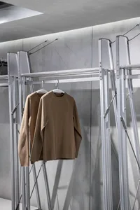 現代室內服裝展示鋁架，展示兩件棕色針織襯衫。