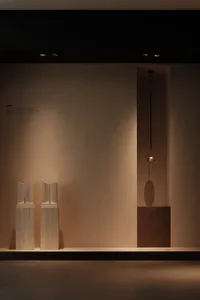 Minimalist display featuring stone columns and a metallic hanging light.