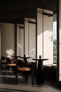 Modern coffee shop interior with wooden furniture, concrete walls, and orange chairs.