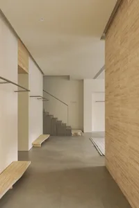 A modern entryway with a concrete floor and steps leading up to a glass door.