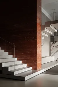 Modern interior space with concrete stairs, glass railings, and marble wall.