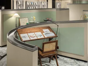 Industrial office space featuring a wooden desk with drafting tools and a lamp.