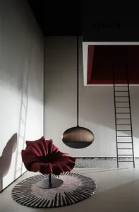 A minimalist interior design featuring a red sculptural chair on a round rug with geometric patterns.