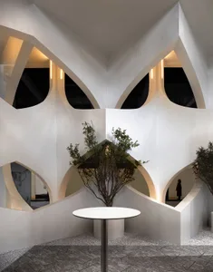 A modern interior design space featuring geometric concrete architecture, intricate lighting fixtures, and a potted green pla