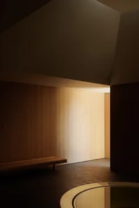 A minimalist interior space featuring wooden paneling with soft, natural lighting.