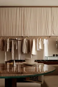 A clothing shop display featuring wood hangers with boho-inspired outfits hanging on a curtain-covered wall.