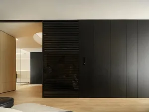 Modern interior design featuring black and wooden furnishings, glass panels, and minimalist decor.