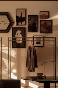 A modern interior with a clothing rack displaying a single sweater, illuminated by sunlight casting geometric shadows on the 