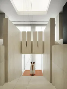 A modern interior design featuring concrete and wood stairs with natural light and high ceilings.