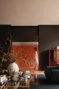 A modern interior living space featuring a large vase with dried flowers, a coffee table with books and decor items, and a pe
