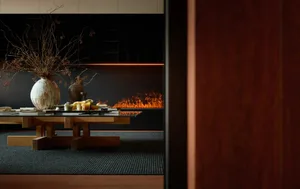 Modern living room featuring a wooden vase, a fireplace with flames, and a black rug.
