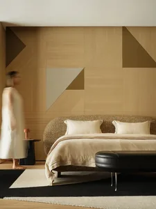 A modern minimalist bedroom featuring a bed with wooden headboard, leather ottoman, and wool bedding.