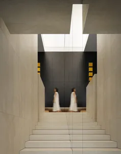 A minimalist interior space with concrete walls and a skylight.