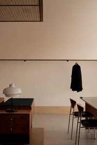 A modern home office featuring a wooden desk, chair, and lamp.