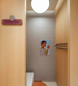 A modern interior with wooden furniture, a patterned wall, and a sign indicating a fitting room.