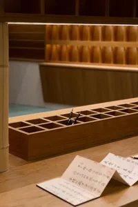 A traditional wooden calligraphy studio with a wooden box containing writing brushes, and handwritten scrolls on the floor.