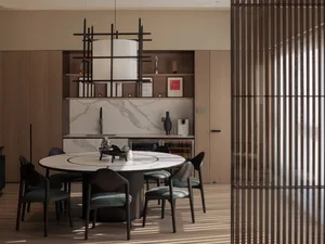 A modern dining room featuring a round marble table surrounded by chairs with green cushions.