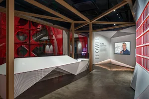 A modern exhibition hall with a red netting structure and concrete flooring.