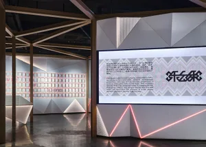 A spacious, modern interior with metallic-textured walls and a large screen displaying text and images.