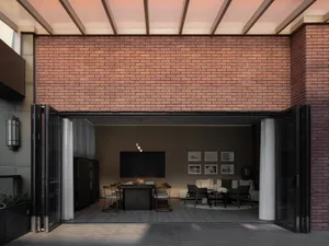 A modern living room with brick walls, featuring dark furniture and a large window.