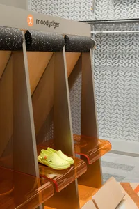 A shoe display furniture piece in a showroom with green clogs.