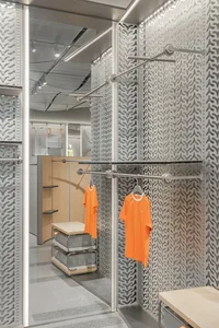 A sophisticated, modern retail store interior featuring modular metallic clothing racks.