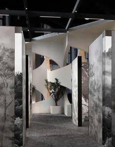 A modern interior with white and gray walls adorned with a tree in a pot and marble columns.
