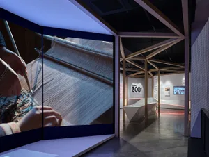 Exhibition space showcasing a weaving demonstration with a focus on industrial design elements and mixed media materials.