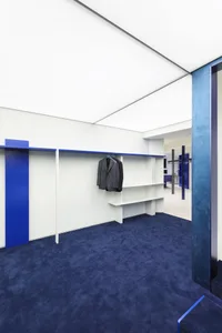 A modern closet with white walls, blue flooring, and a metal storage system.