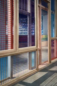 Modern interior featuring red, blue, and pink metal gratings on wooden frames
