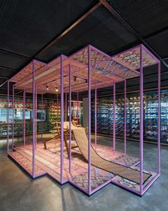 A colorful, patterned space with a textile weaving loom and a variety of yarn spools on display.