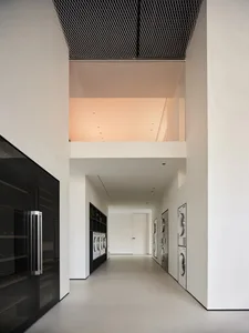 現代極簡洗衣間，配有光滑的白混凝土地板與牆面，以及精巧的家電與洗衣籃。