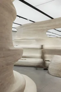 Modern interior with wooden curved structures and a person walking through the space.