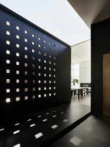 Modern kitchen with black wooden walls featuring a grid of cut-out windows.