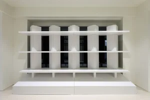 A modern, minimalist interior with white shelves and structural elements.