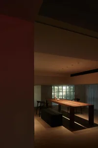 Modern minimalist dining room with wooden table and chairs, geometric lighting, and minimalist decor.