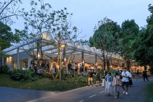 A modern public space featuring glass walls, metal structures, and fabric elements.